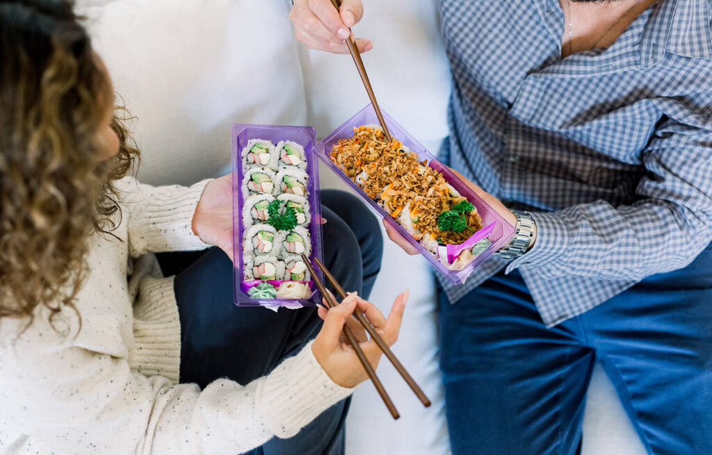 Two people sharing a container of sushi